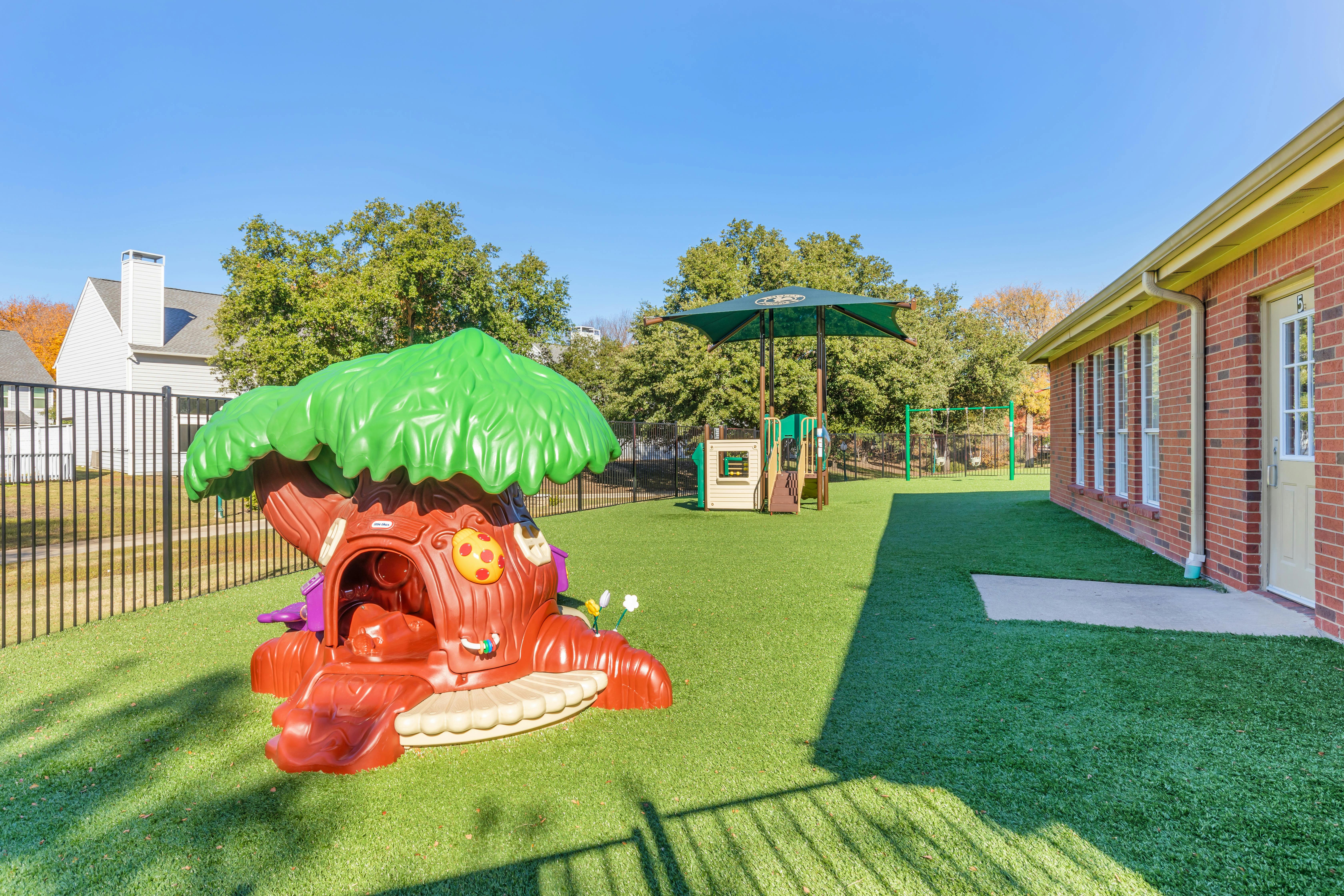 Playground with an artificial turf ground, a treehouse, and a swing set