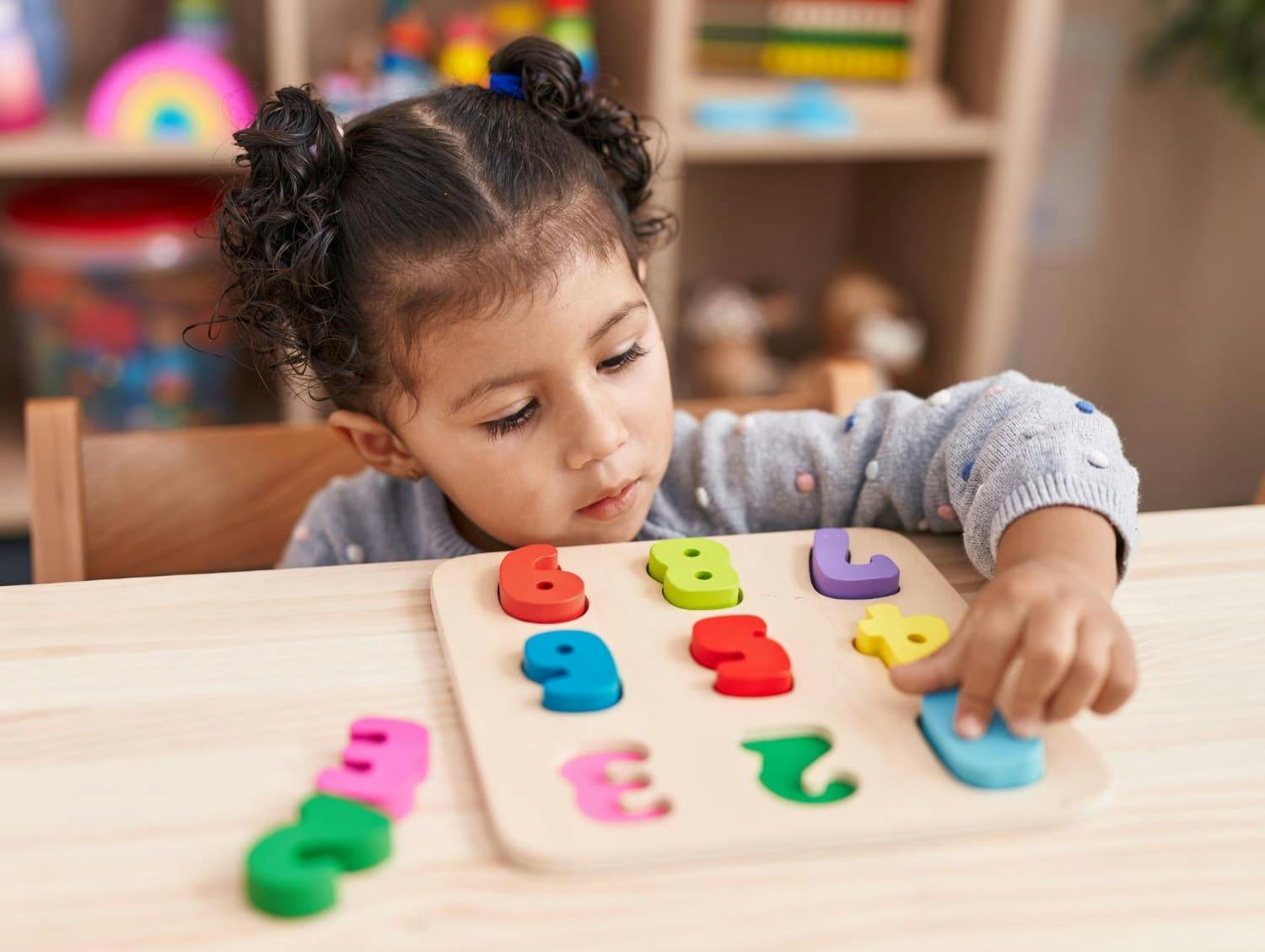 Child playing with a wooden number puzzle at a table