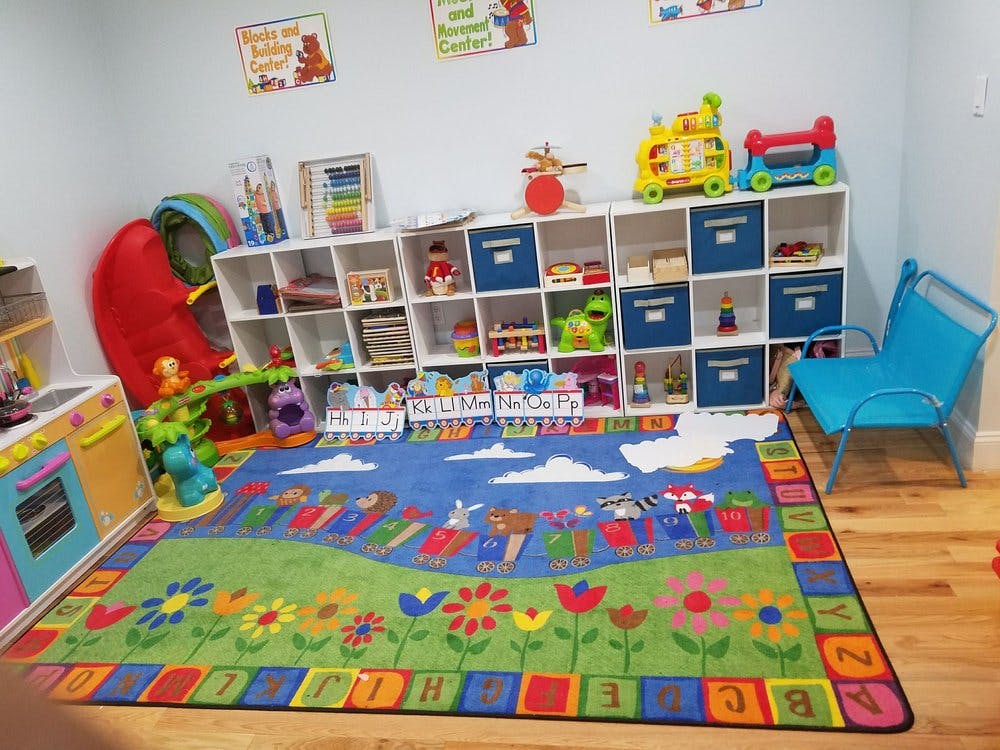 Playroom with colorful rug, toy shelves, and child-sized furniture