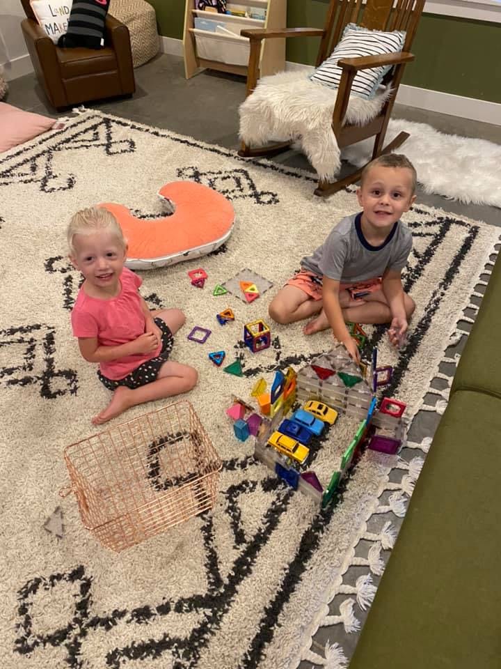 Two children playing with toys on a rug