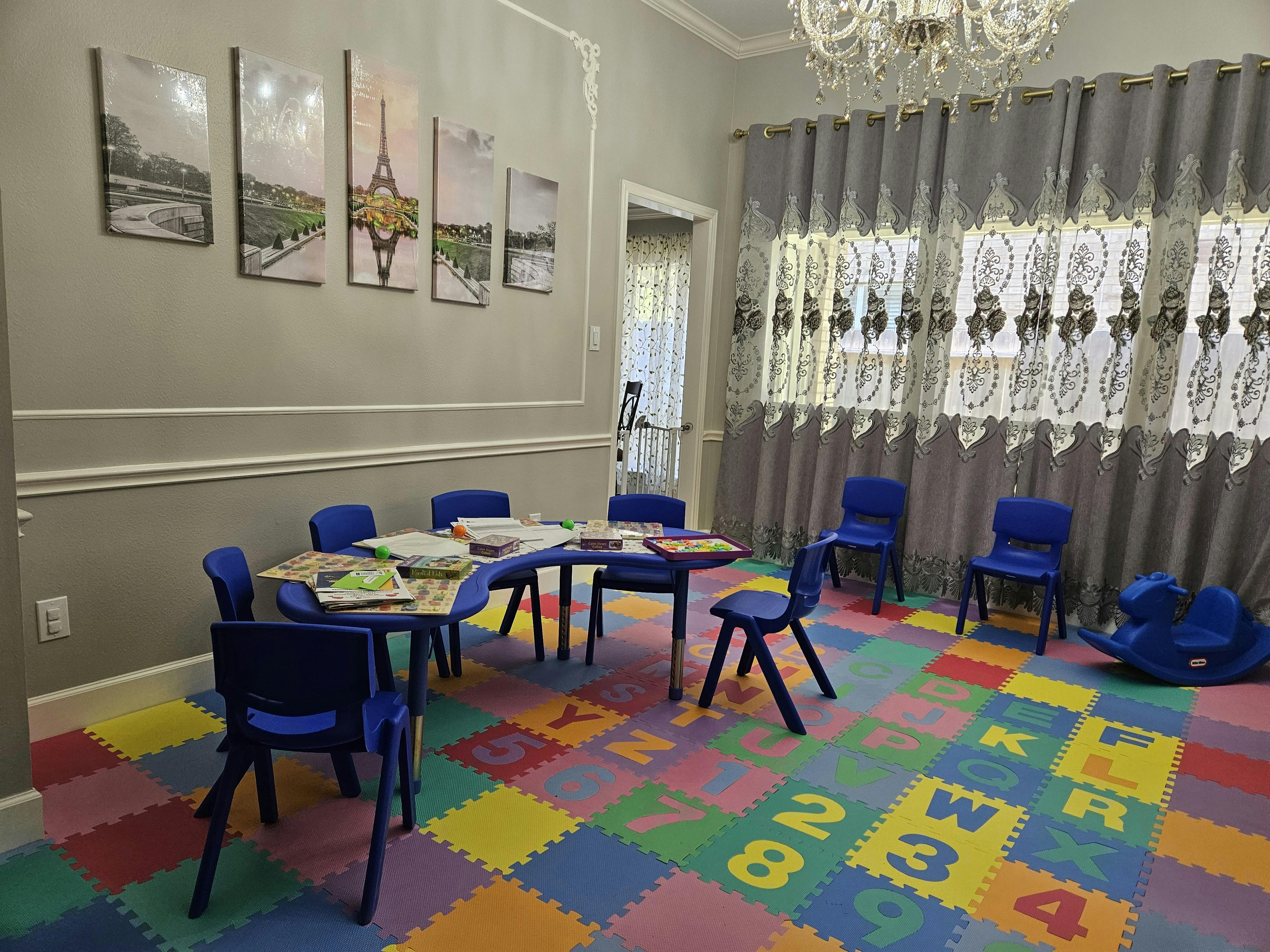 Playroom with small blue tables and chairs on a colorful alphabet and number mat