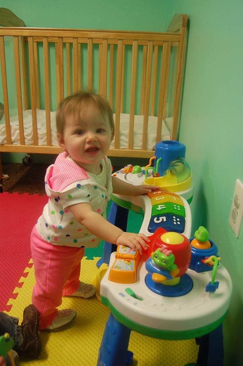 Child standing and playing with a colorful activity table
