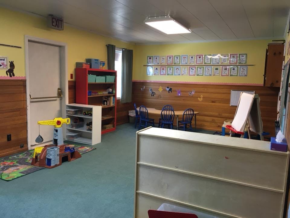 Classroom with small tables and chairs, shelves, and an easel