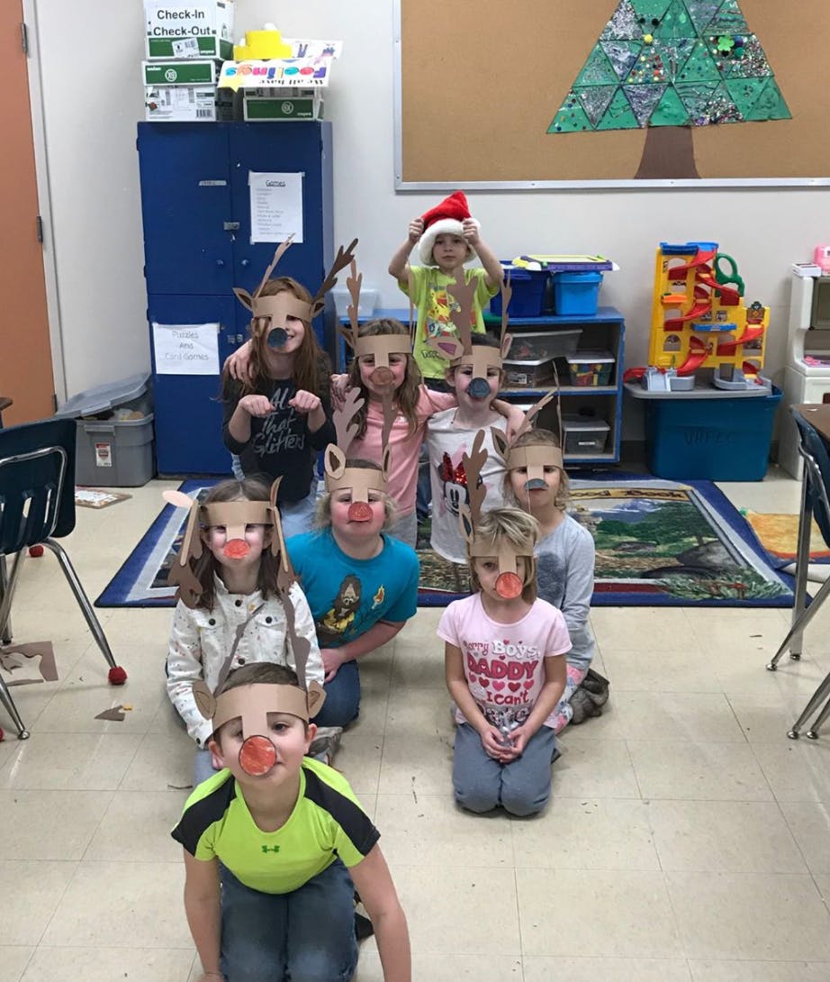 Group of children wearing reindeer masks and one child wearing a Santa hat