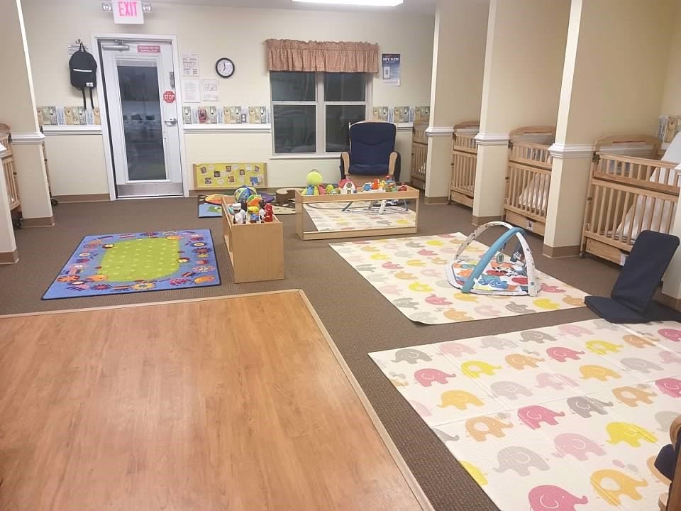Baby room with multiple cribs, playmats, and toys