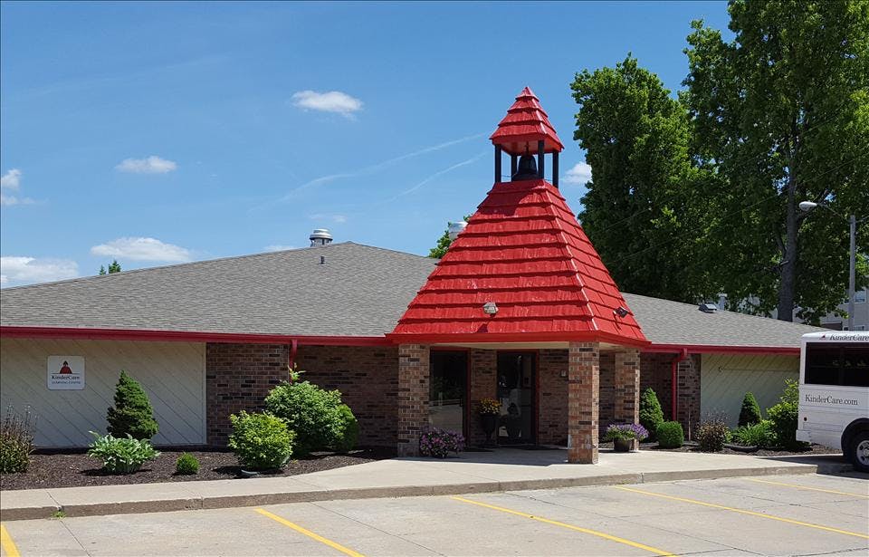 Building with a red pointed roof over the entrance and a bell tower
