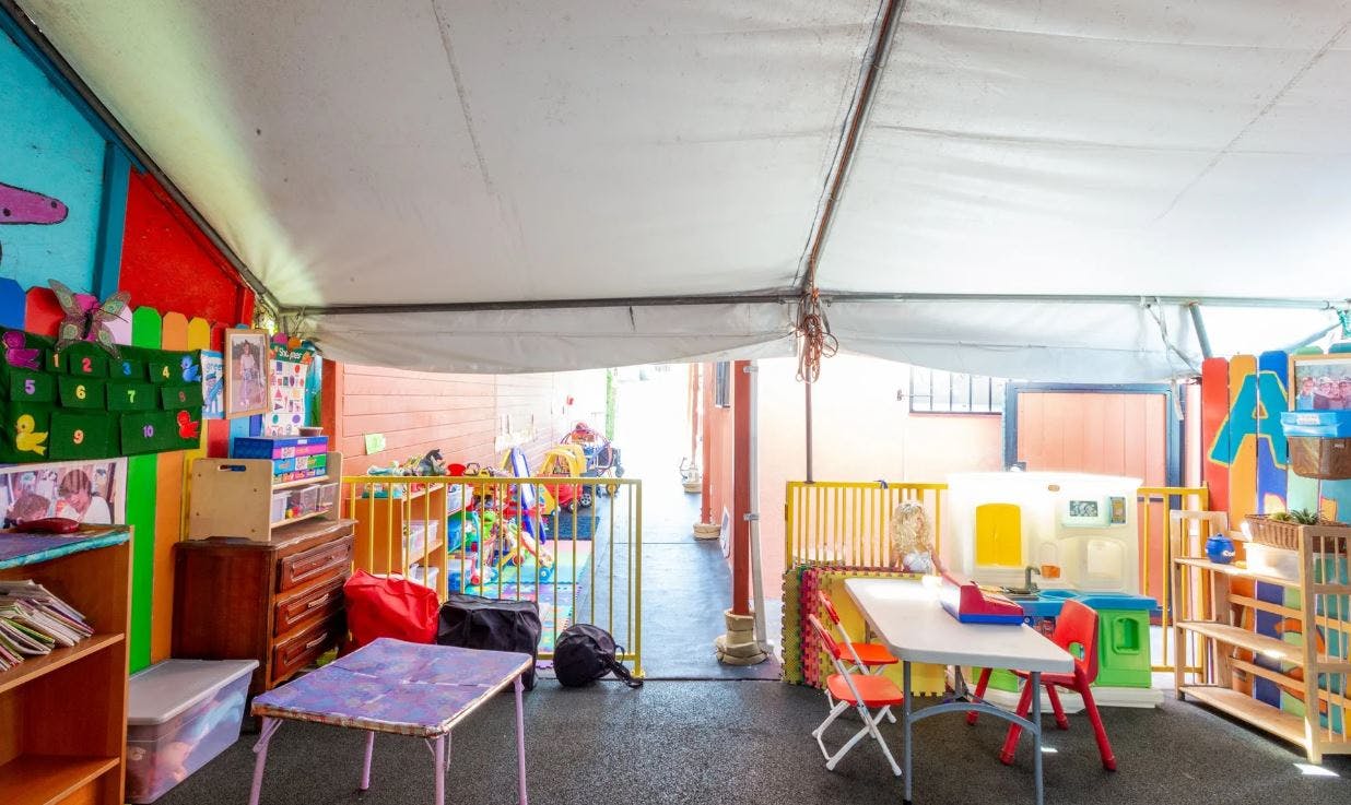 Playroom with small tables and chairs under a tent-like roof