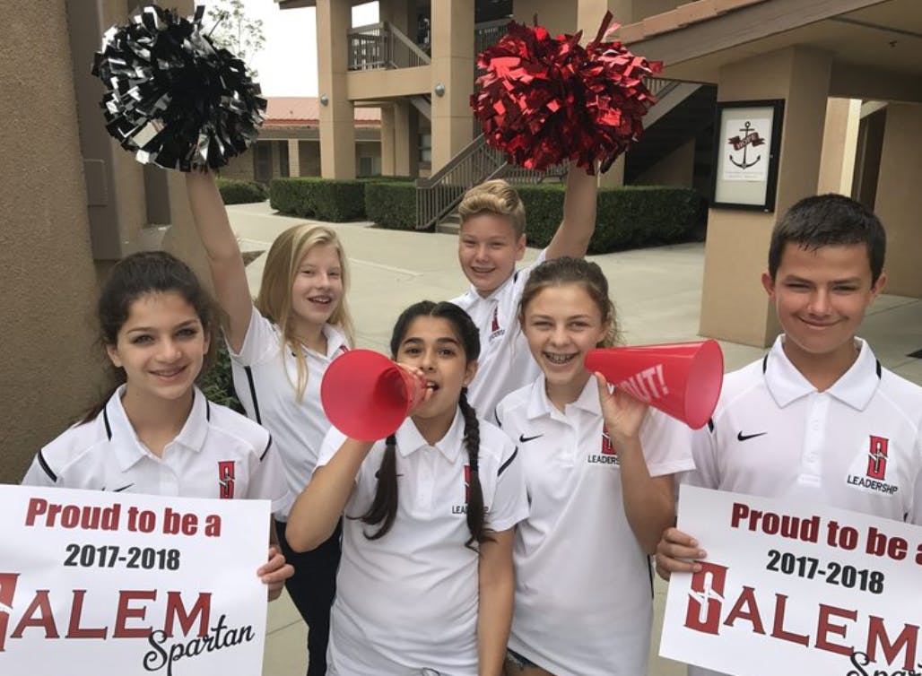 Group of children holding signs, pom-poms, and megaphones
