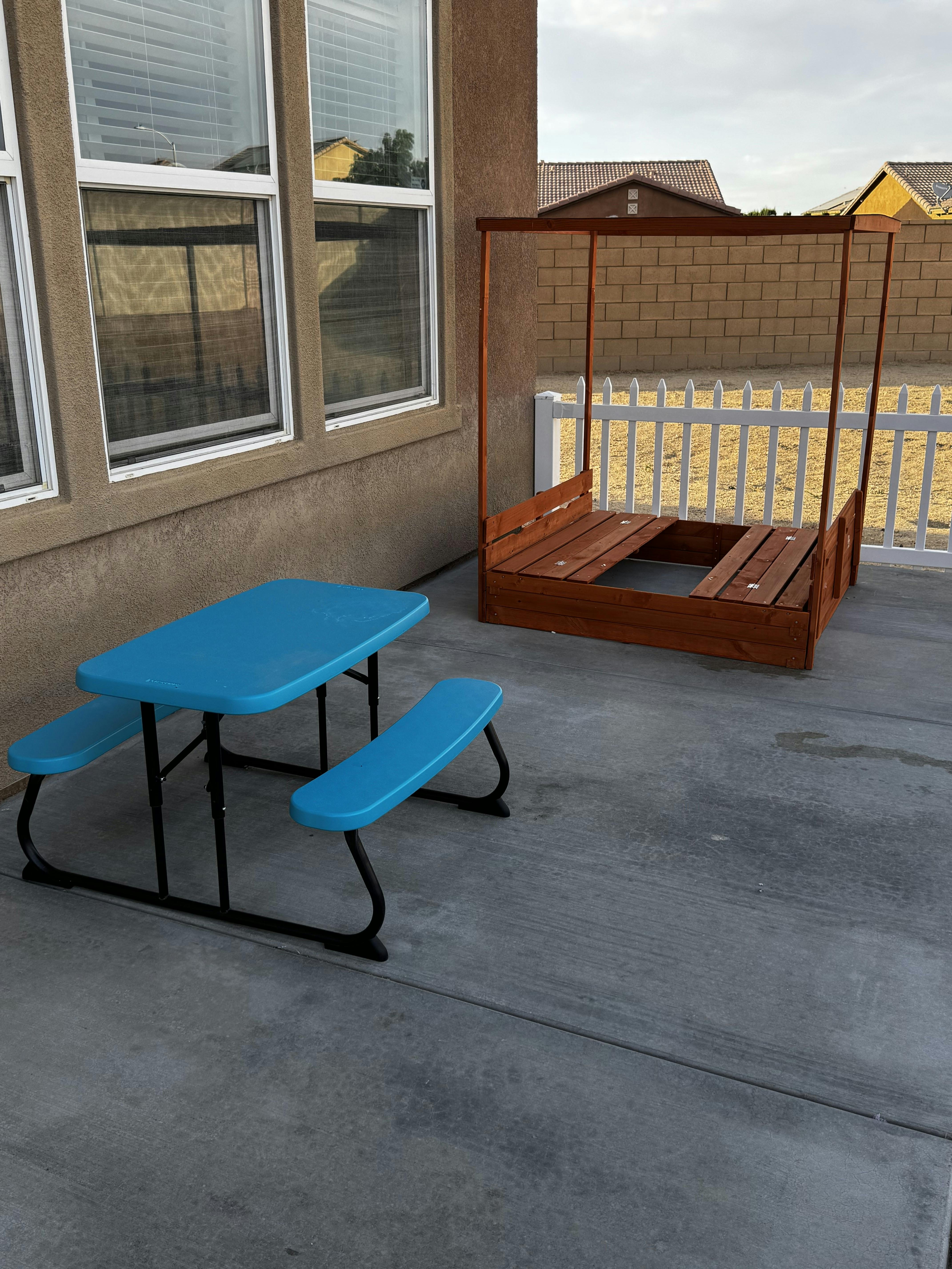 Blue children's picnic table and wooden sandbox on a patio