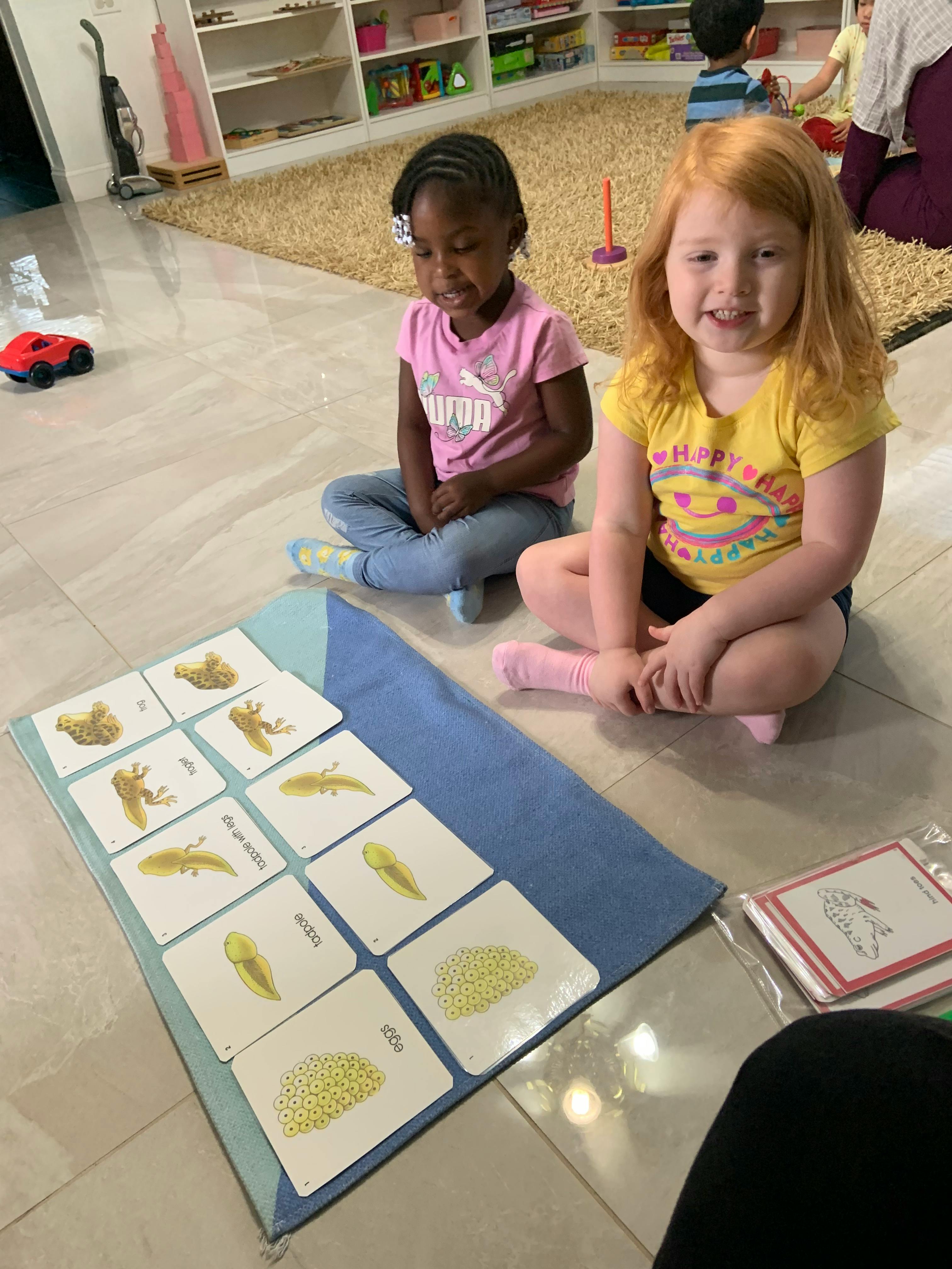 Two children sitting on the floor with educational cards