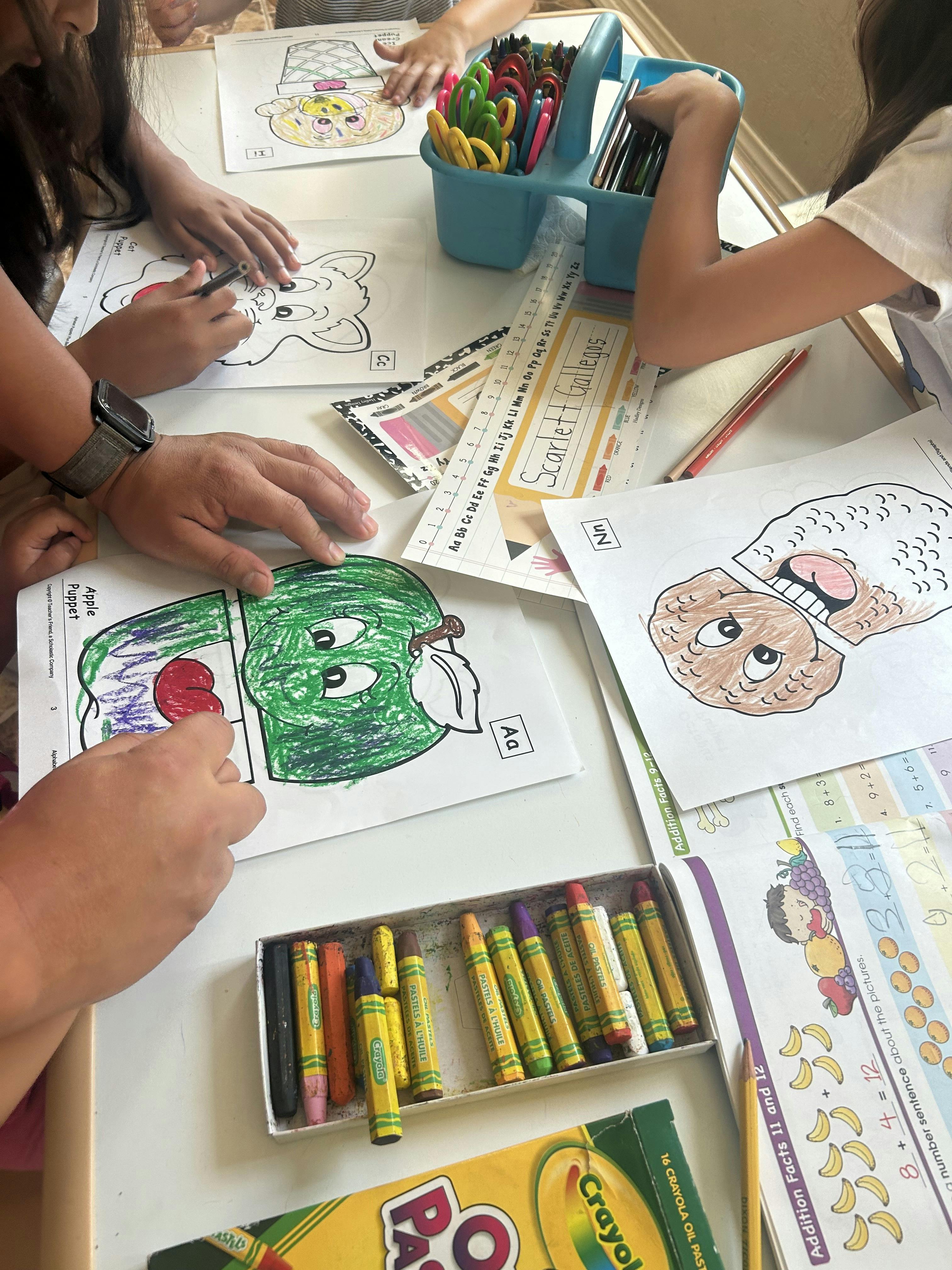 Children coloring at a table with crayons and coloring pages