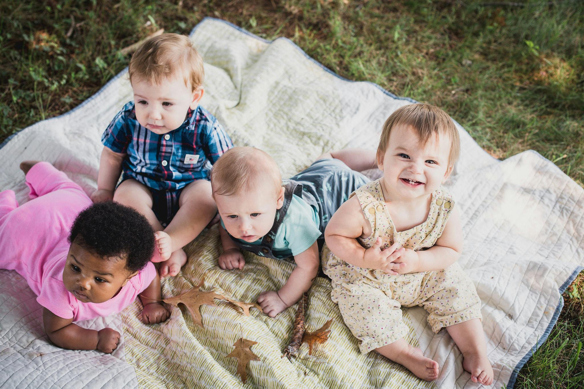 Four babies on a blanket outdoors