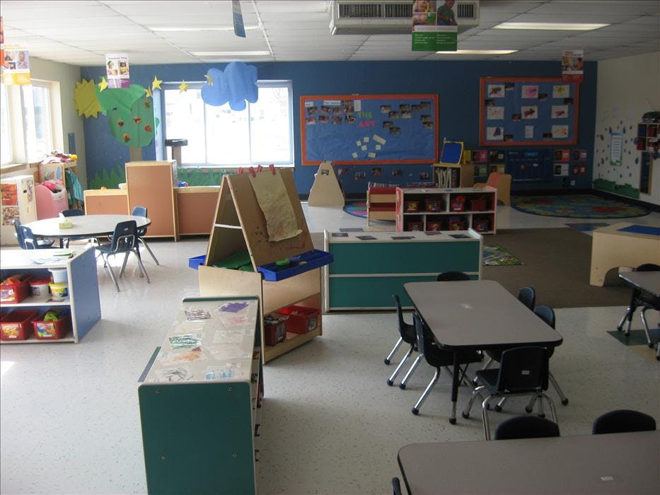 An empty early childhood classroom with small tables, chairs, and learning centers