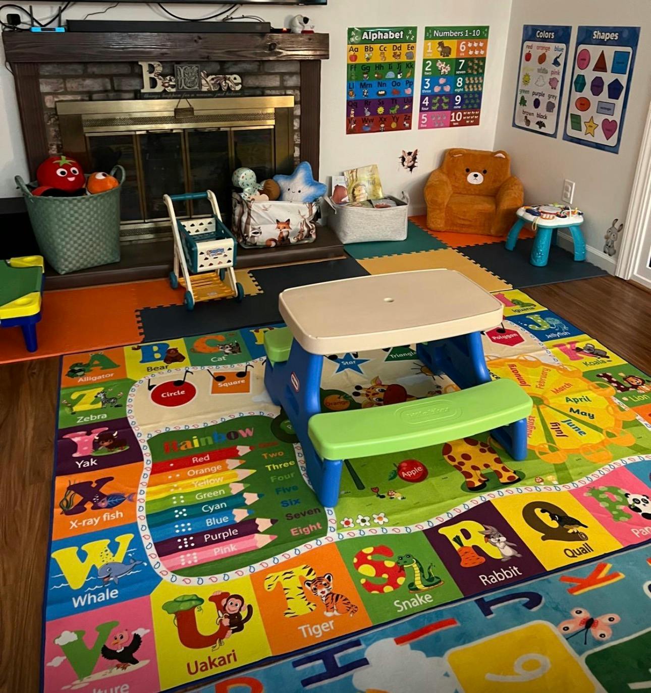 Children's play area with alphabet rug, small table and chair, and toy baskets