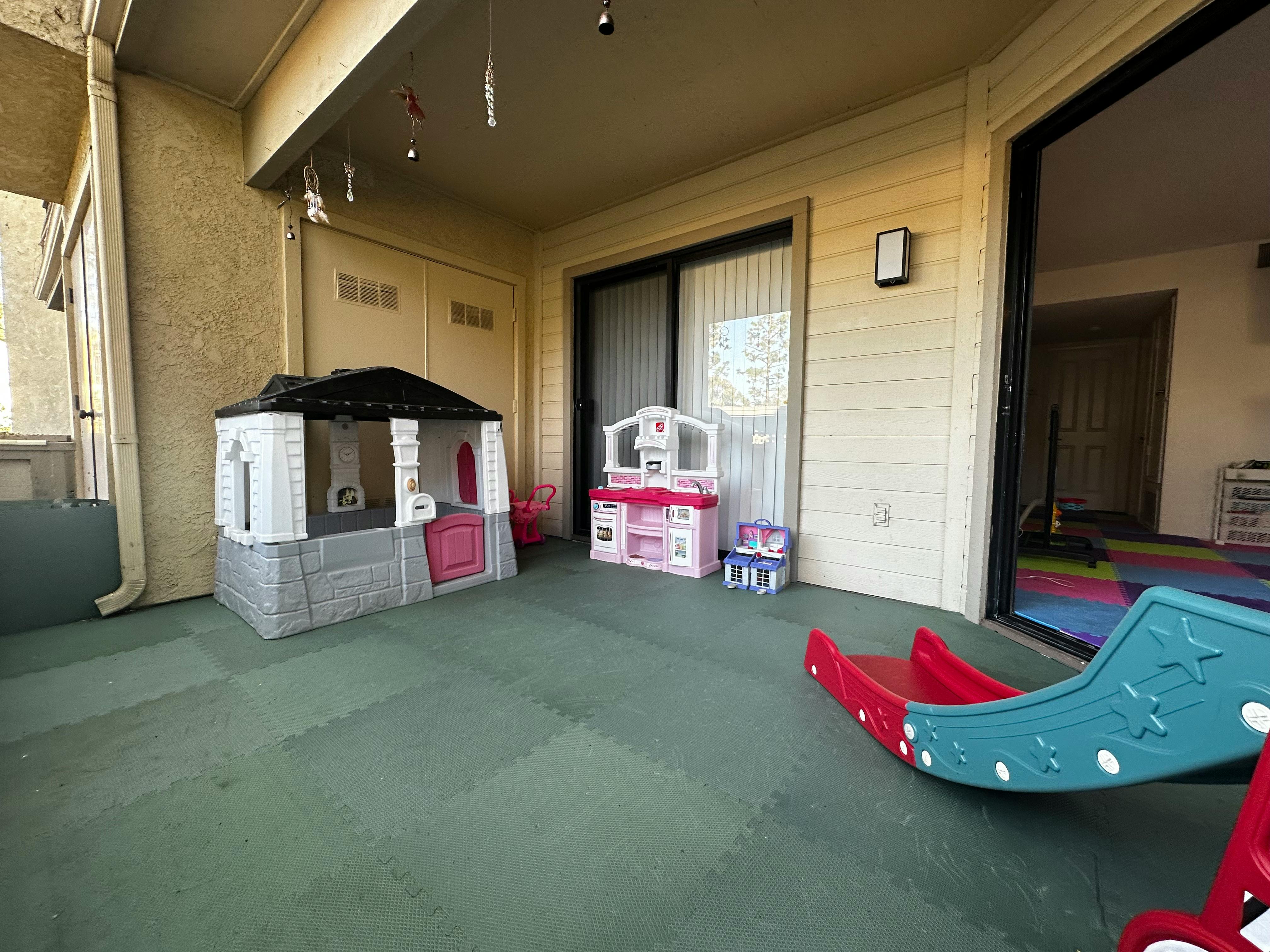 Playhouse, toy kitchen, and slide on a patio
