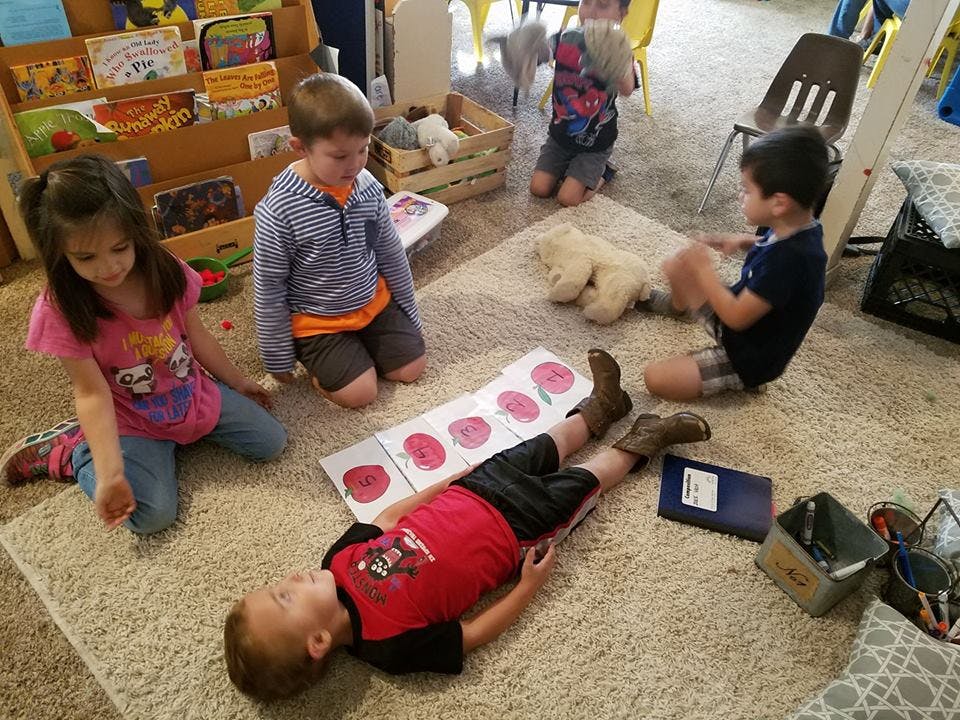 Children playing on a rug in a classroom