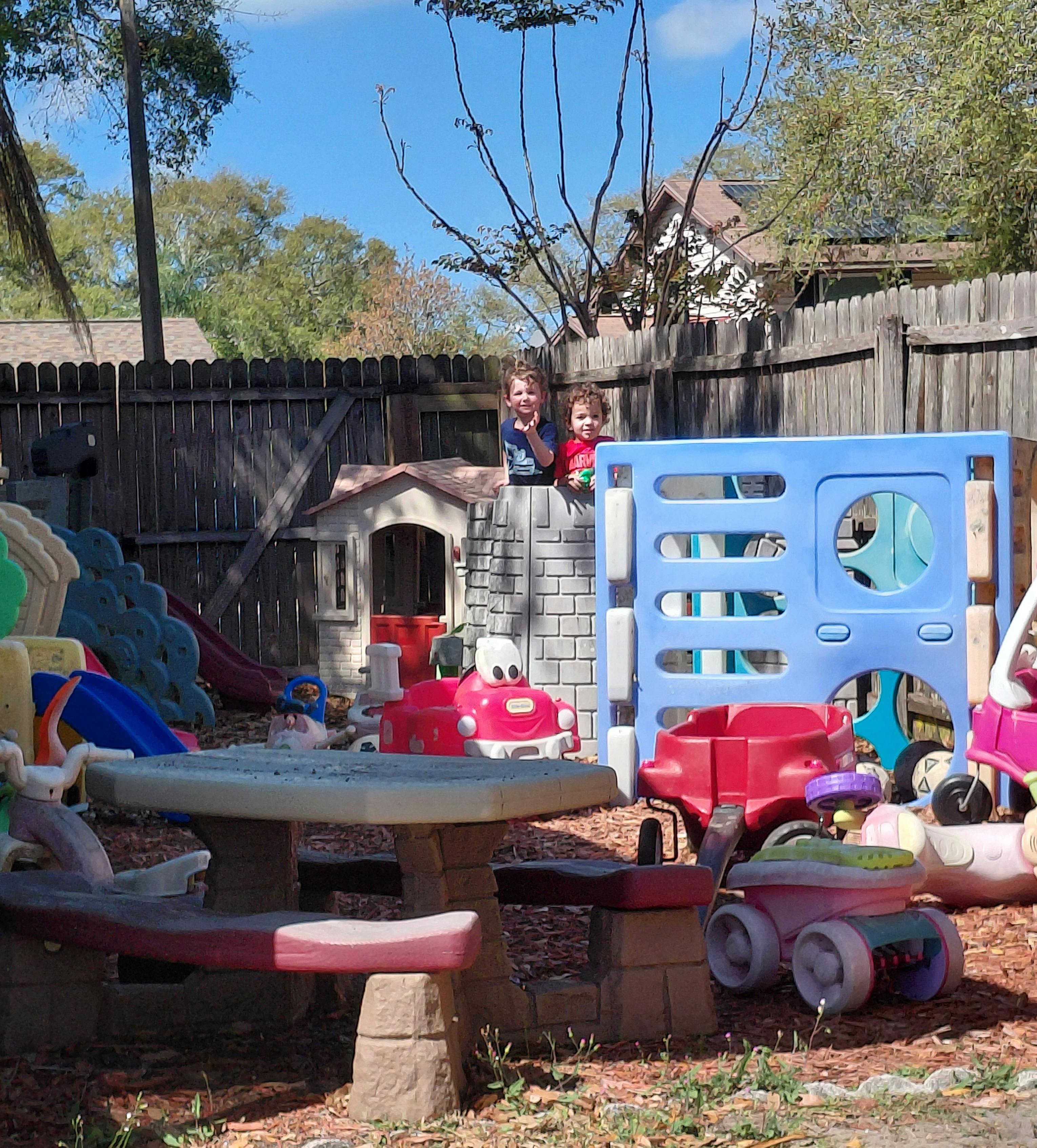 Two children standing inside a toy castle in a backyard