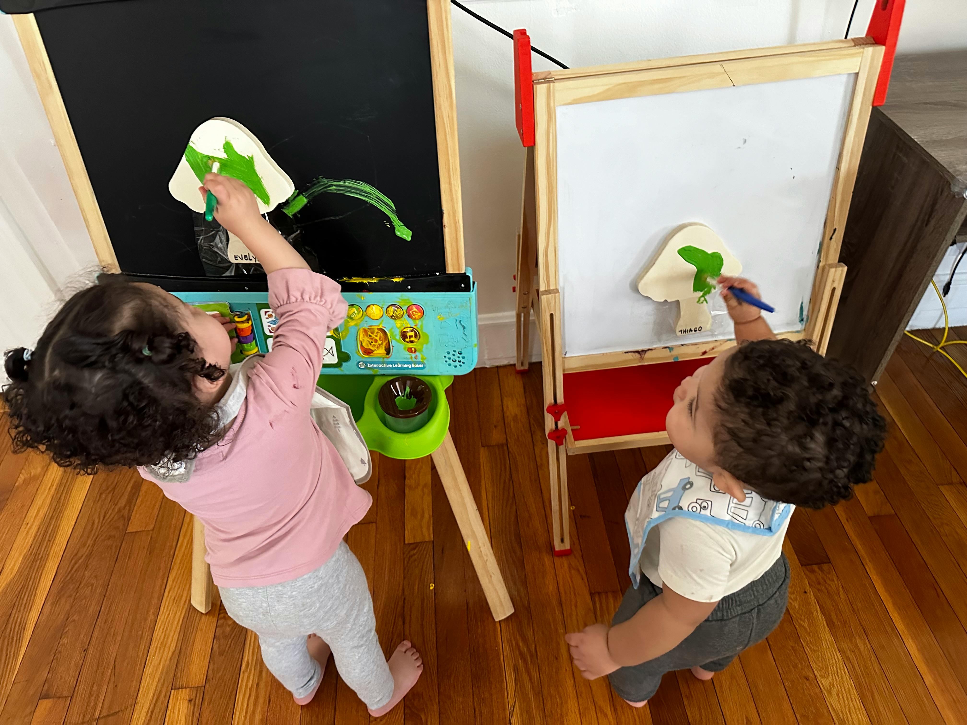 Two children drawing on easels