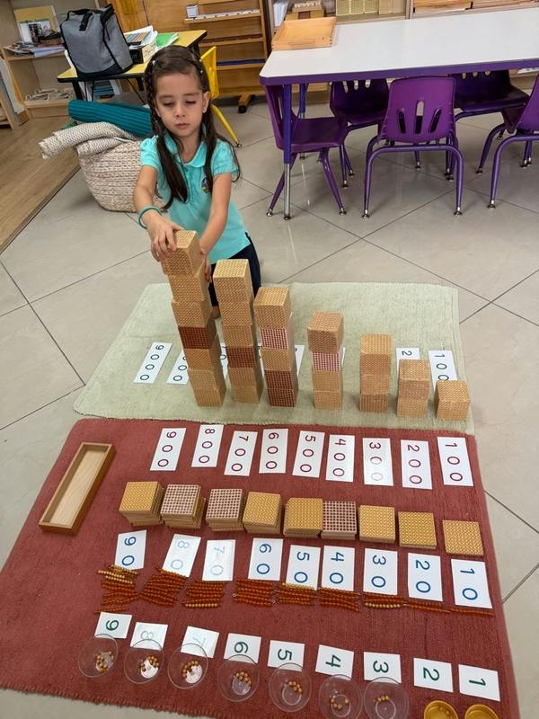 Child building a tower with math blocks on a classroom rug