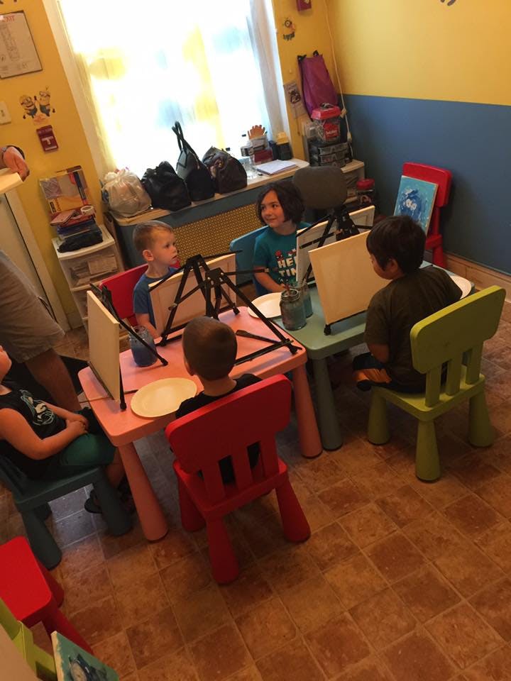 Children painting at easels in a classroom