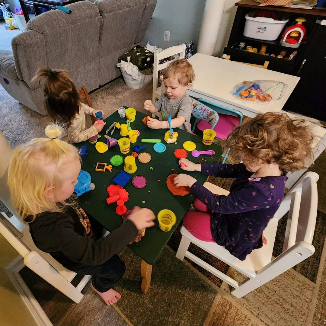 Four children playing with colorful modeling clay at a table