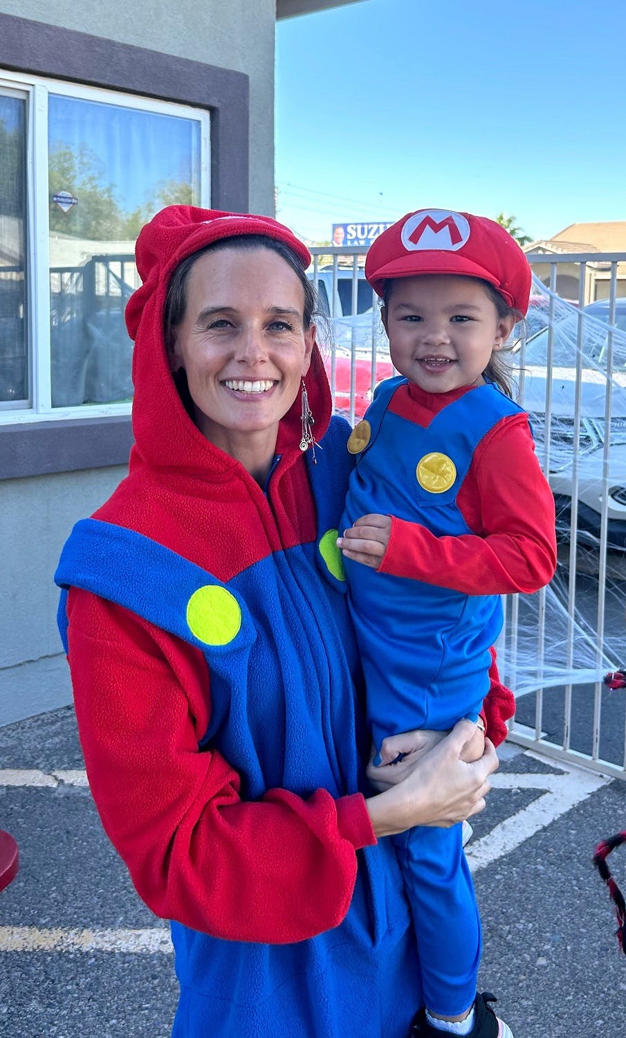Person holding a child, both dressed in red and blue costumes