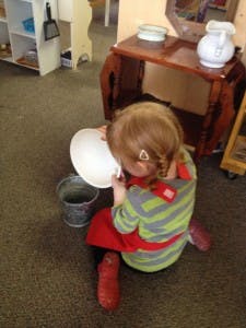 Child playing with a bowl and bucket on the floor