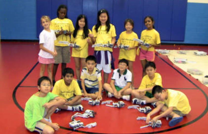 Group of children and teens with robots on a gym floor