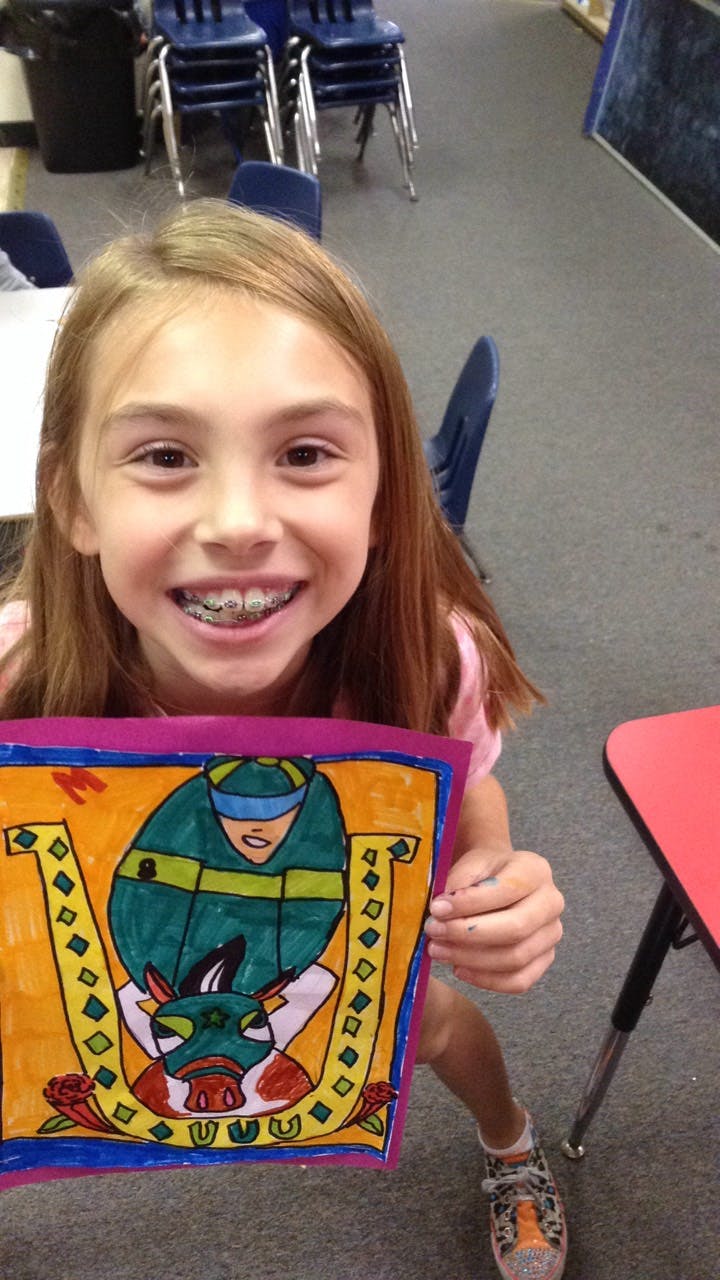 Child holding up a colorful drawing of a figure and a bull