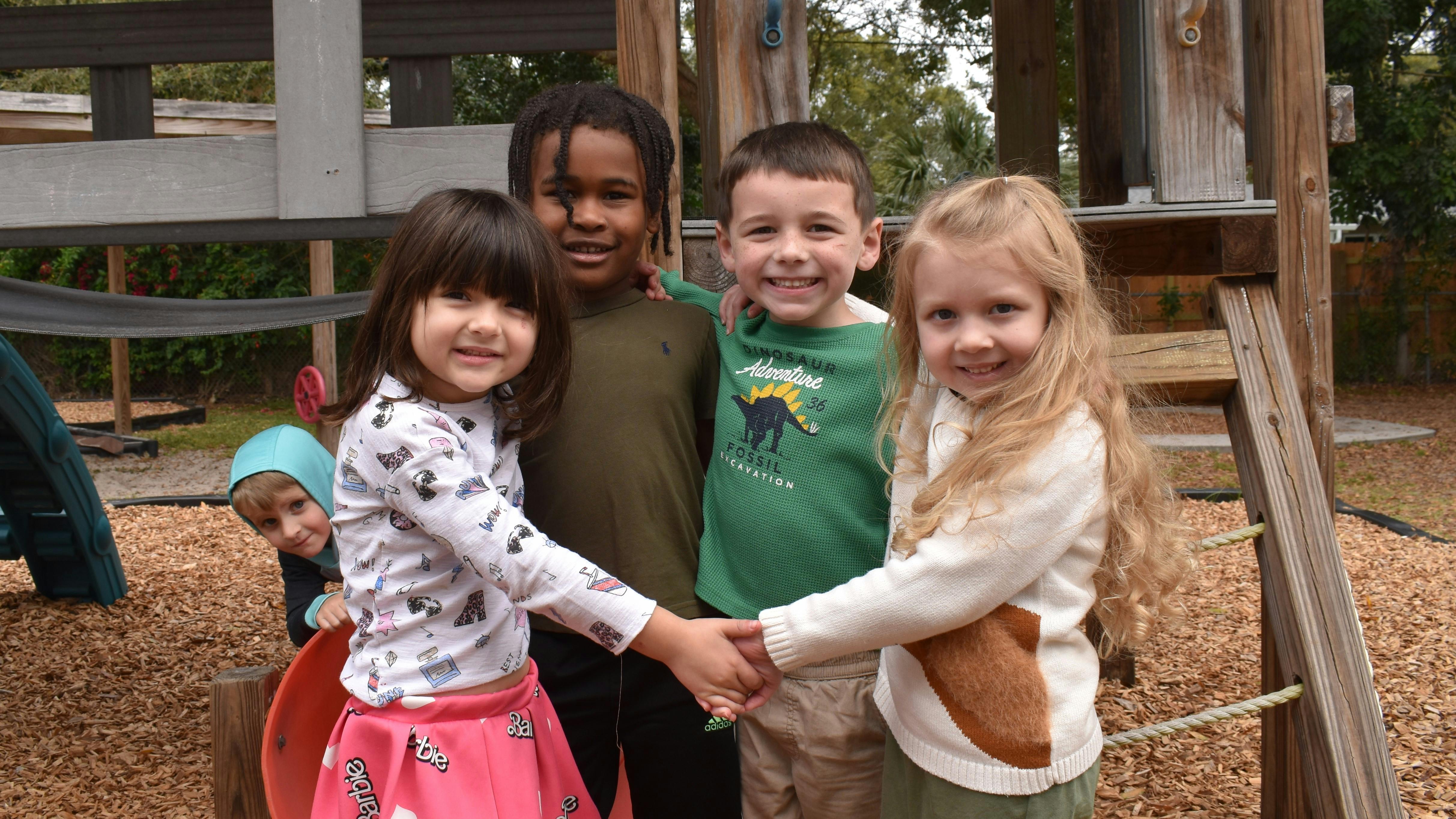Four children holding hands on a playground