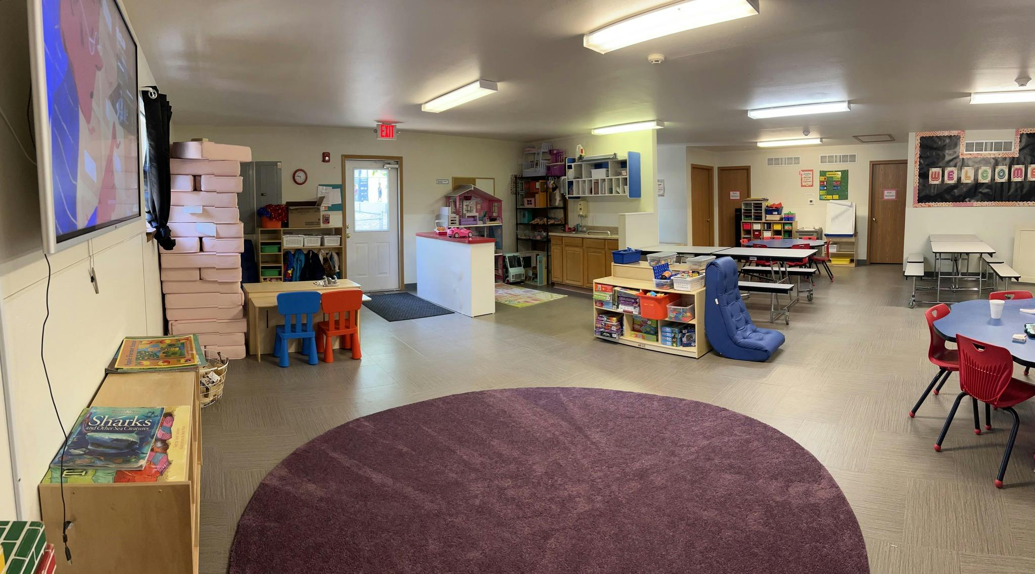 Playroom with small tables and chairs, bookshelves, and a round rug
