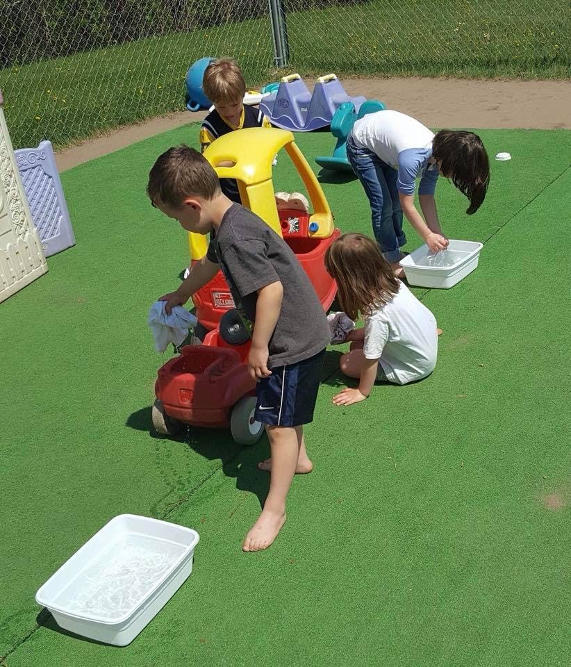 Children playing with water and toys on green ground