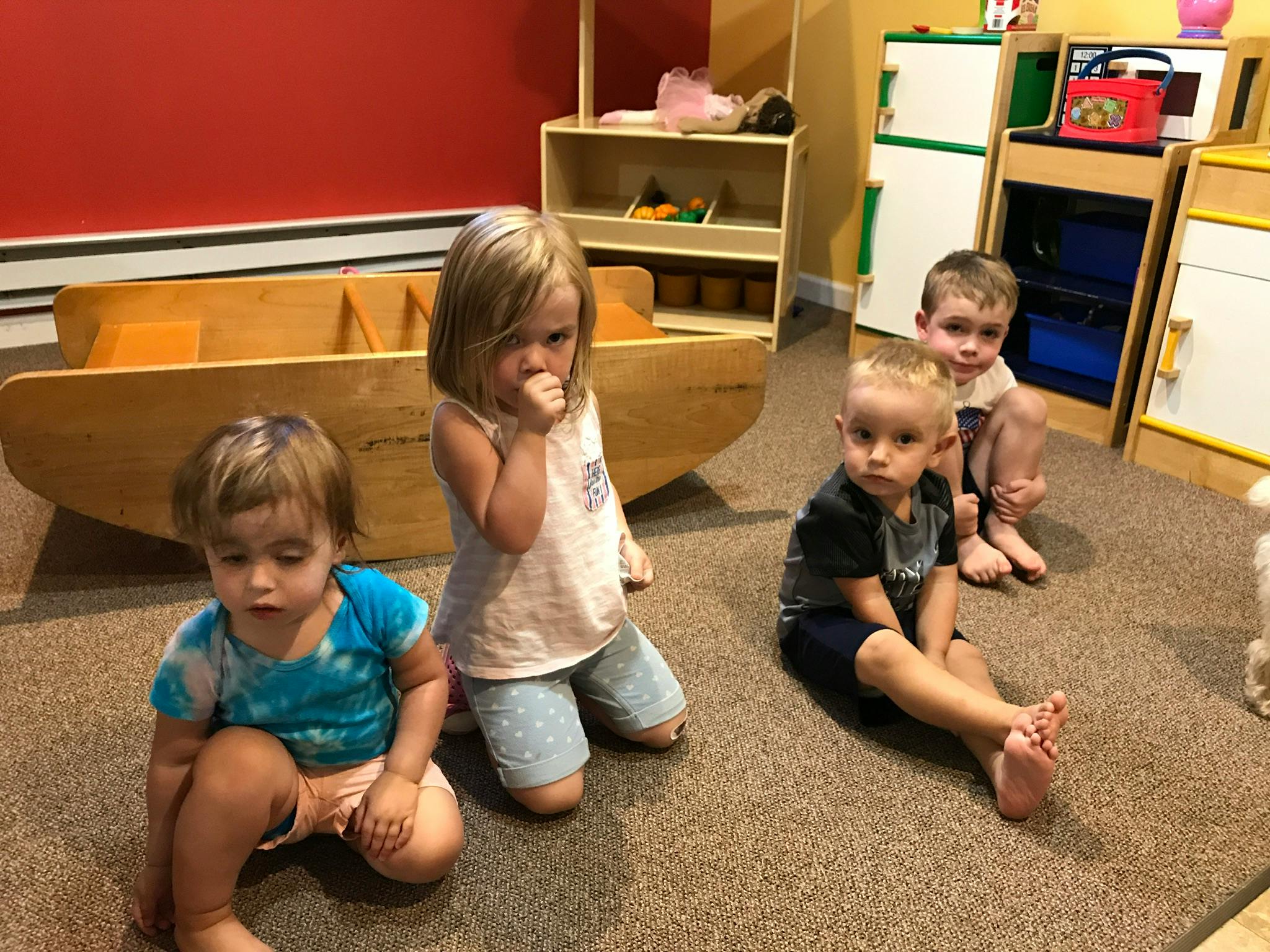 Four children sitting on the floor in a classroom