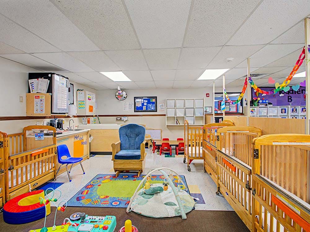 Daycare room with multiple cribs, a rocking chair, and play mats