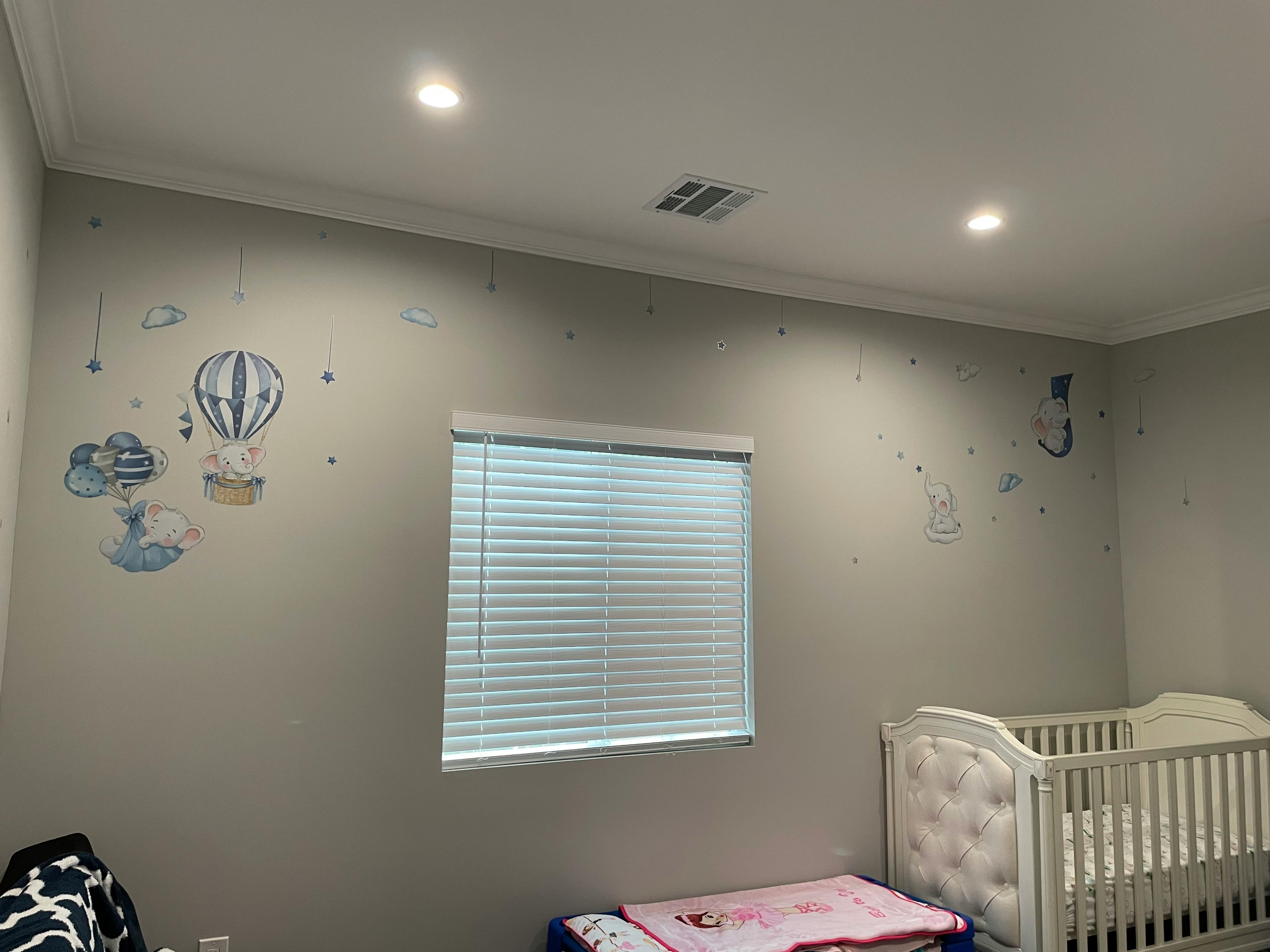 Nursery room with hot air balloon wall decals, window, and crib
