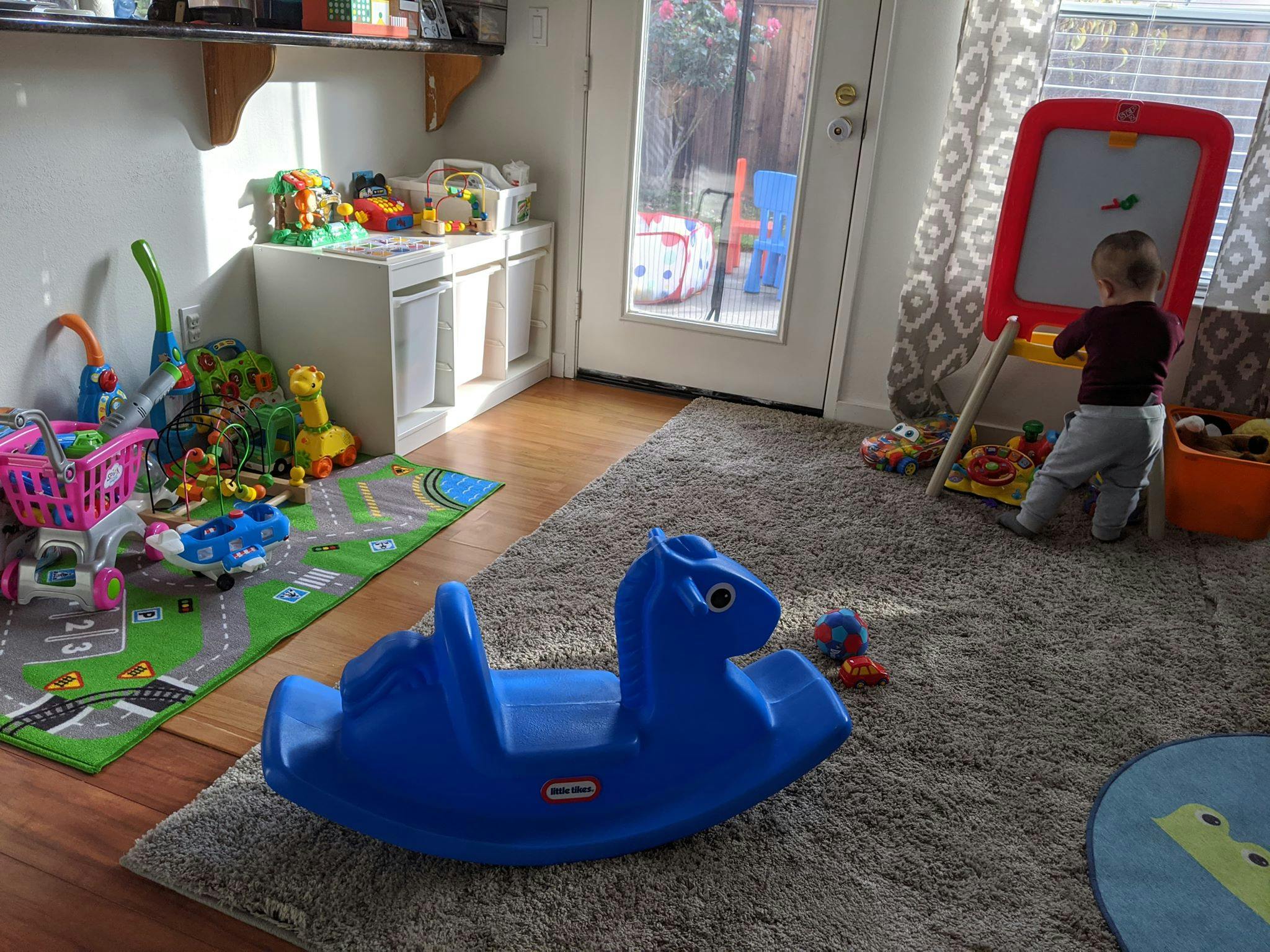 Child kneeling at an easel in a playroom with toys