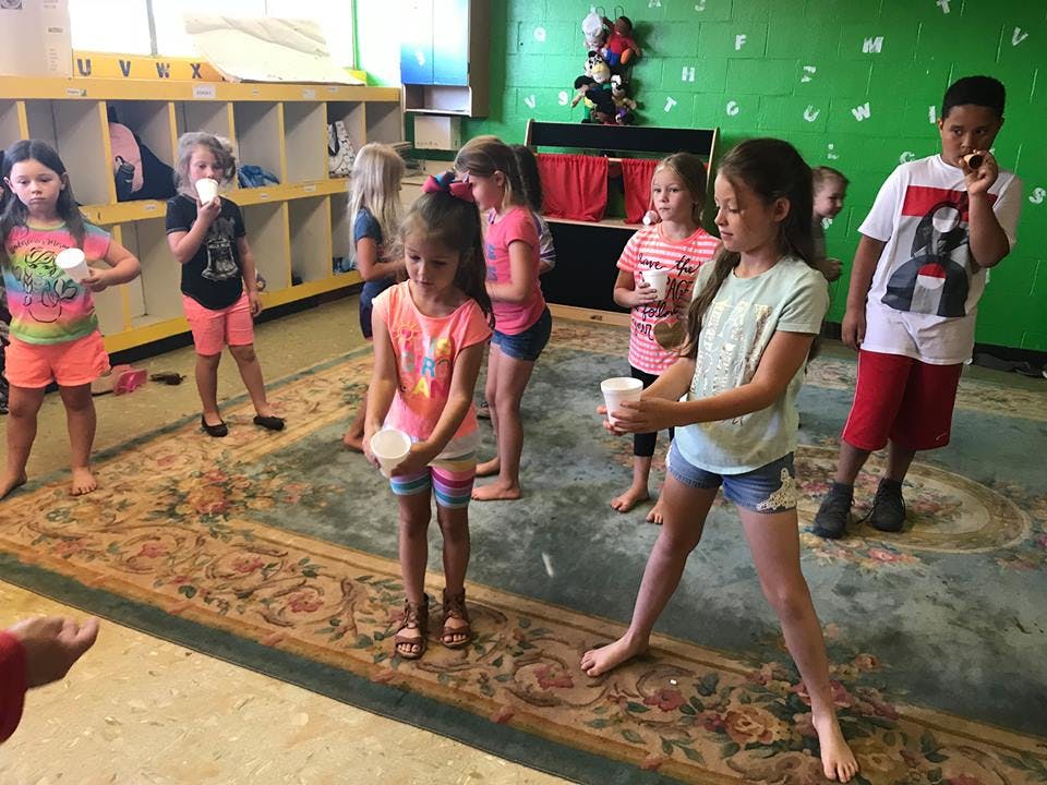 Children holding cups in a classroom