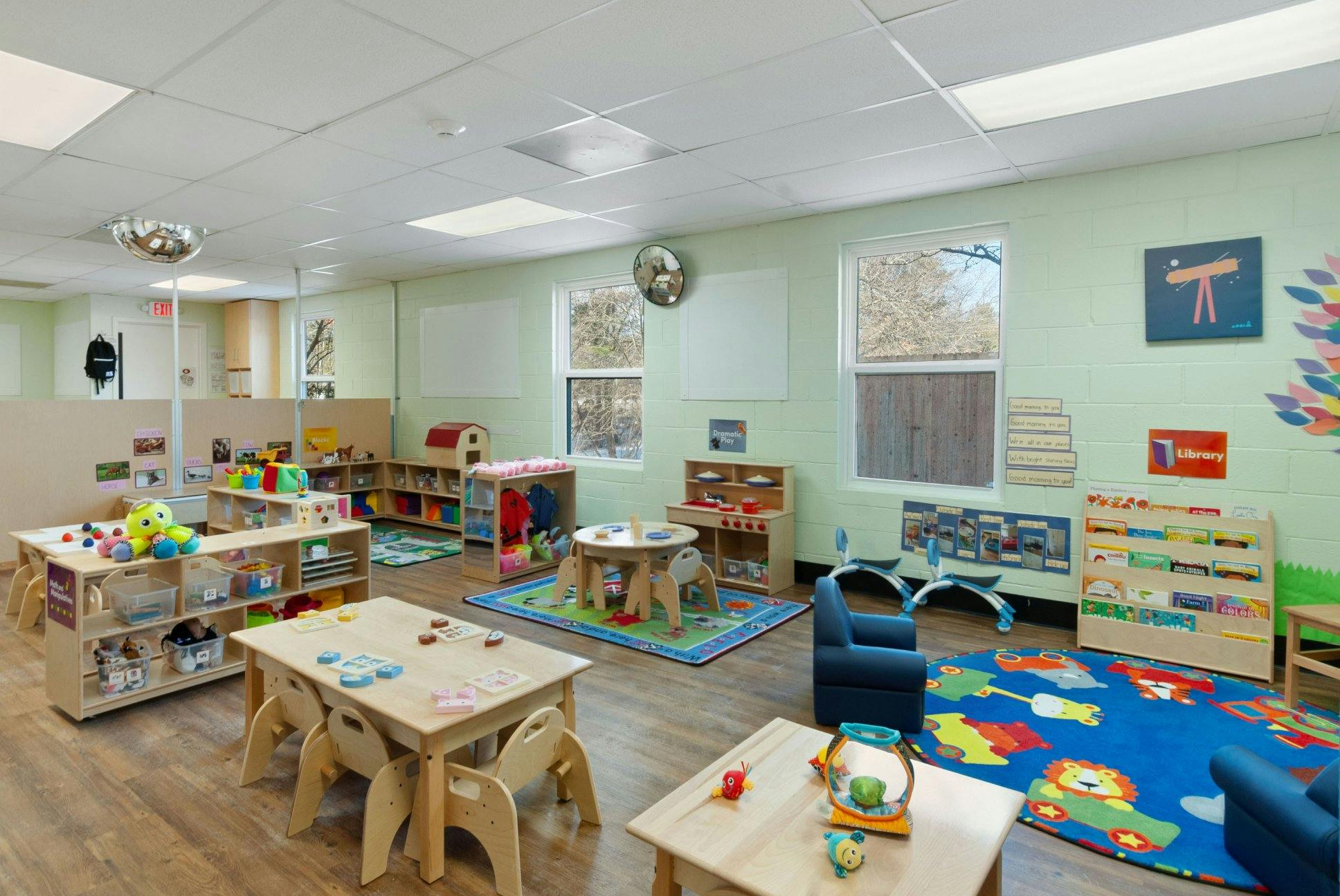 brightly lit classroom with various activity stations and child-sized furniture