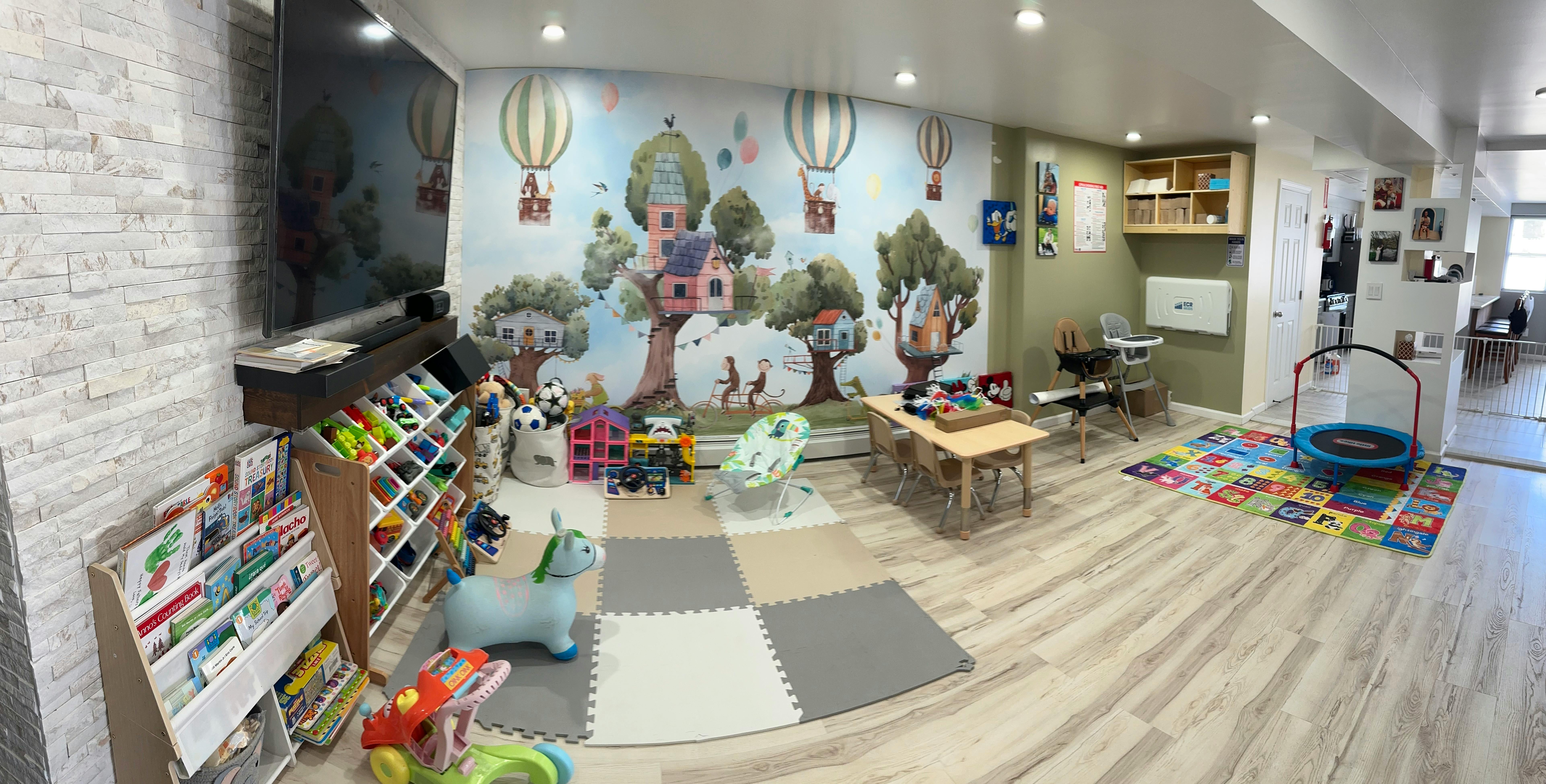 Playroom with mural, toy shelves, small table, and trampoline