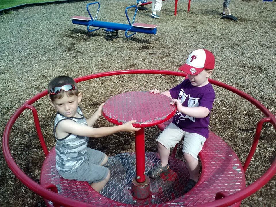 Two children on a red merry-go-round at a playground