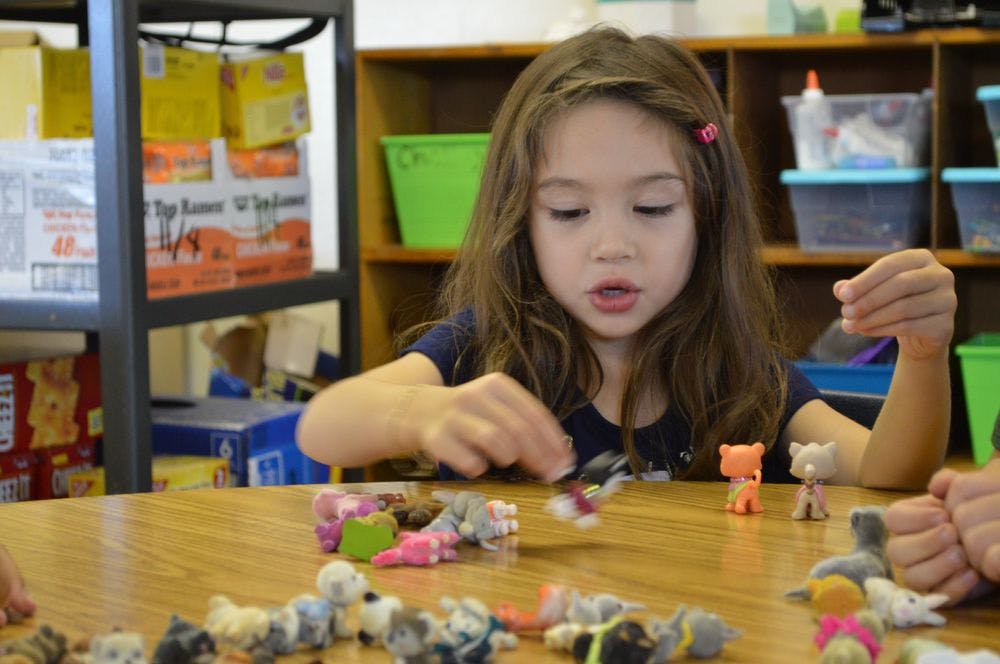 Child playing with small toys on a table