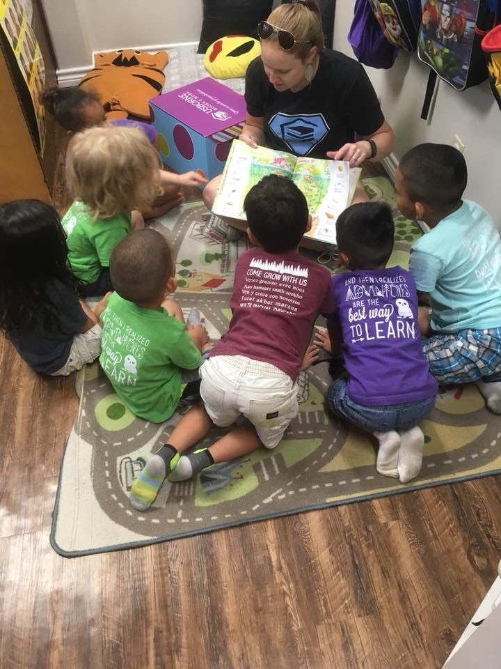 Adult reading a book to a group of children sitting on a rug