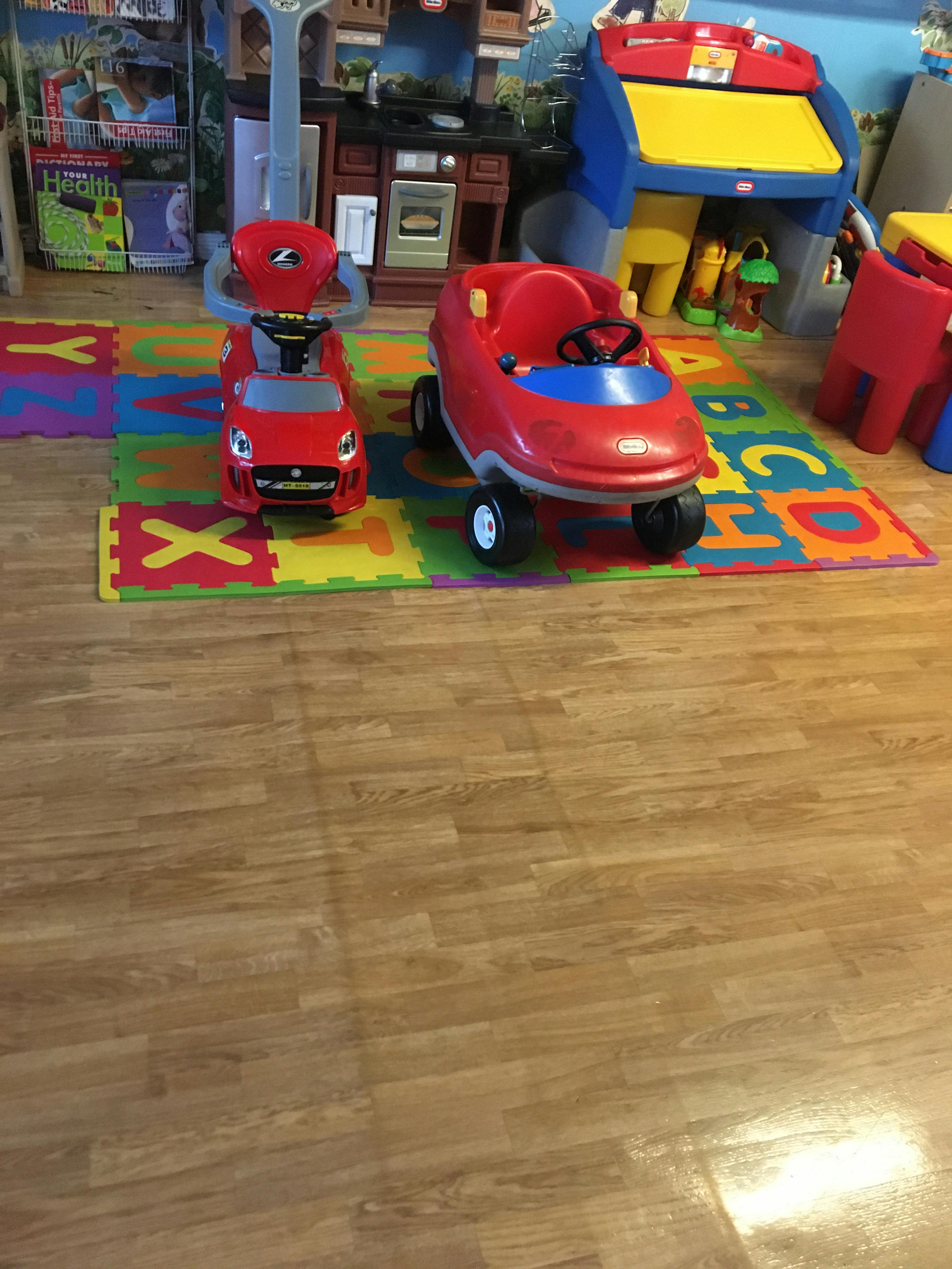 Two red toy cars on a colorful alphabet playmat