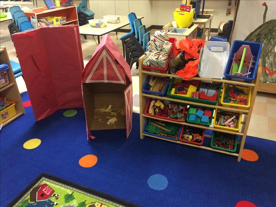 Classroom with toy storage, a cardboard playhouse, and a rug with colorful dots