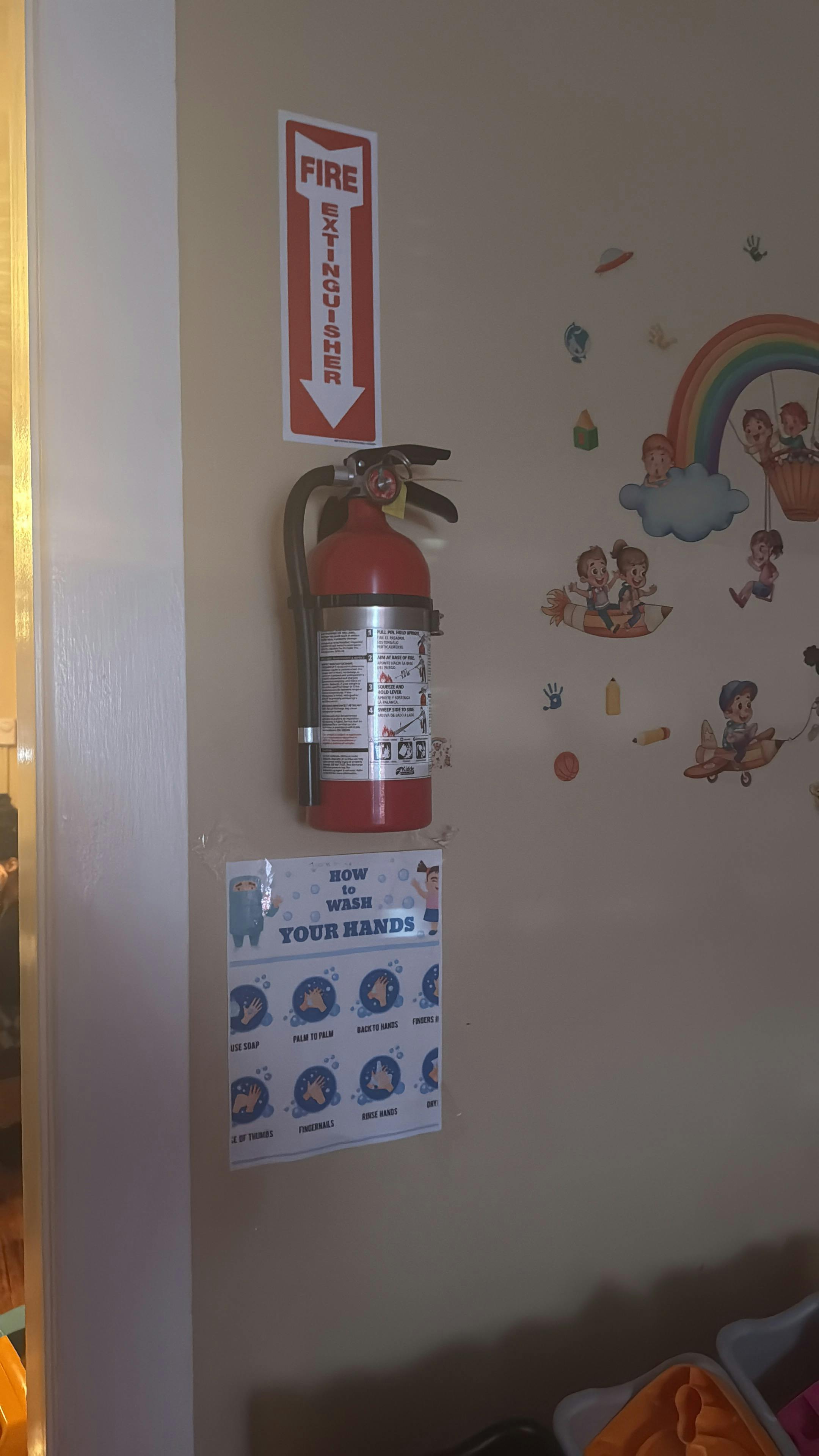 Fire extinguisher mounted on a wall with a "FIRE EXTINGUISHER" sign above it