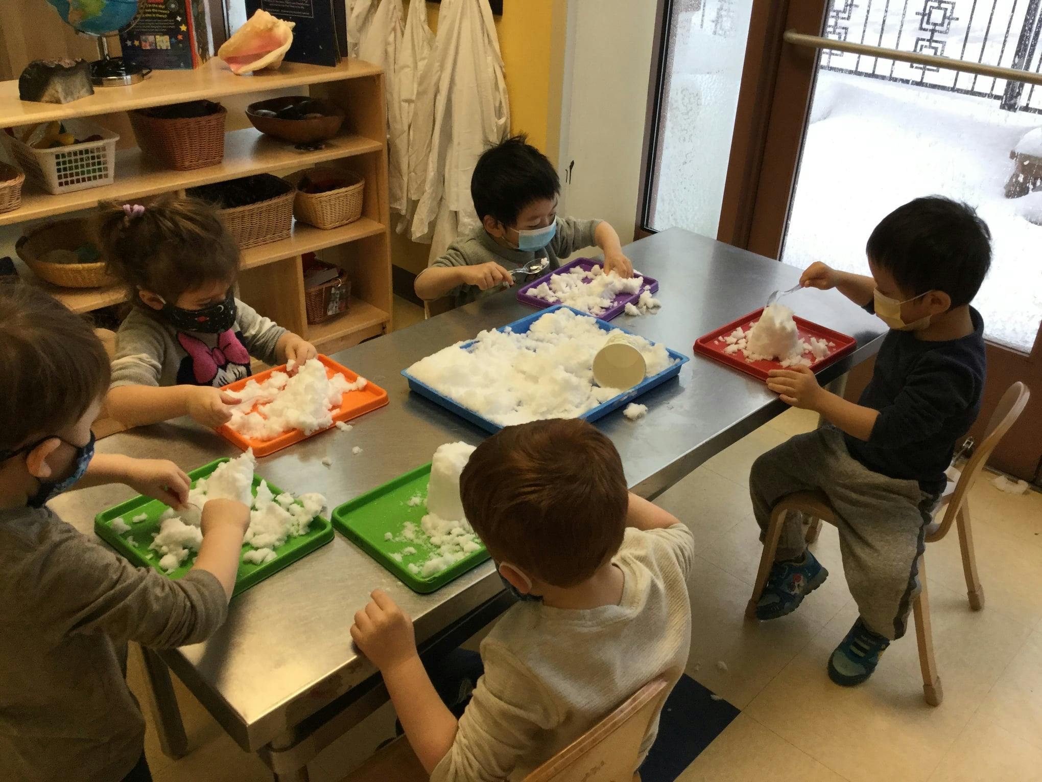 Children playing with snow at a table