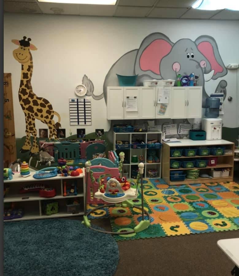 Childcare room with animal murals, shelves of toys, and play mats
