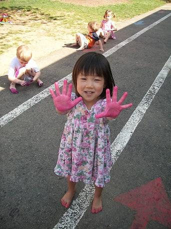 Child with pink paint on hands, other children in background