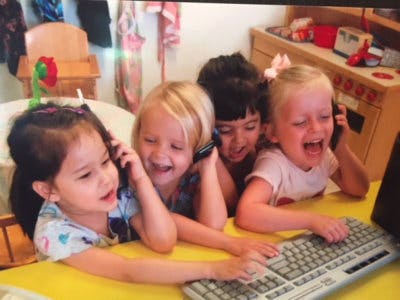 Four children playing with toy phones and a computer keyboard