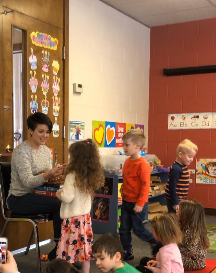 Adult person interacting with children in a classroom